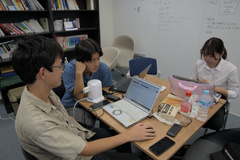 複数人がコンピュータに向かって考えている写真