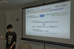 発表者とスクリーンが移っており、発表者が施策について話している写真